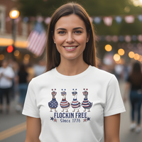 Load image into Gallery viewer, Woman wearing a white t-shirt with a graphic design and text, standing in a festive outdoor setting.